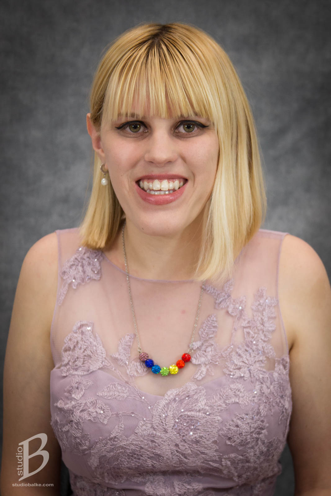 Janna Morrison Headshot. She is wearing a lilac dress with a rainbow beaded necklace. 